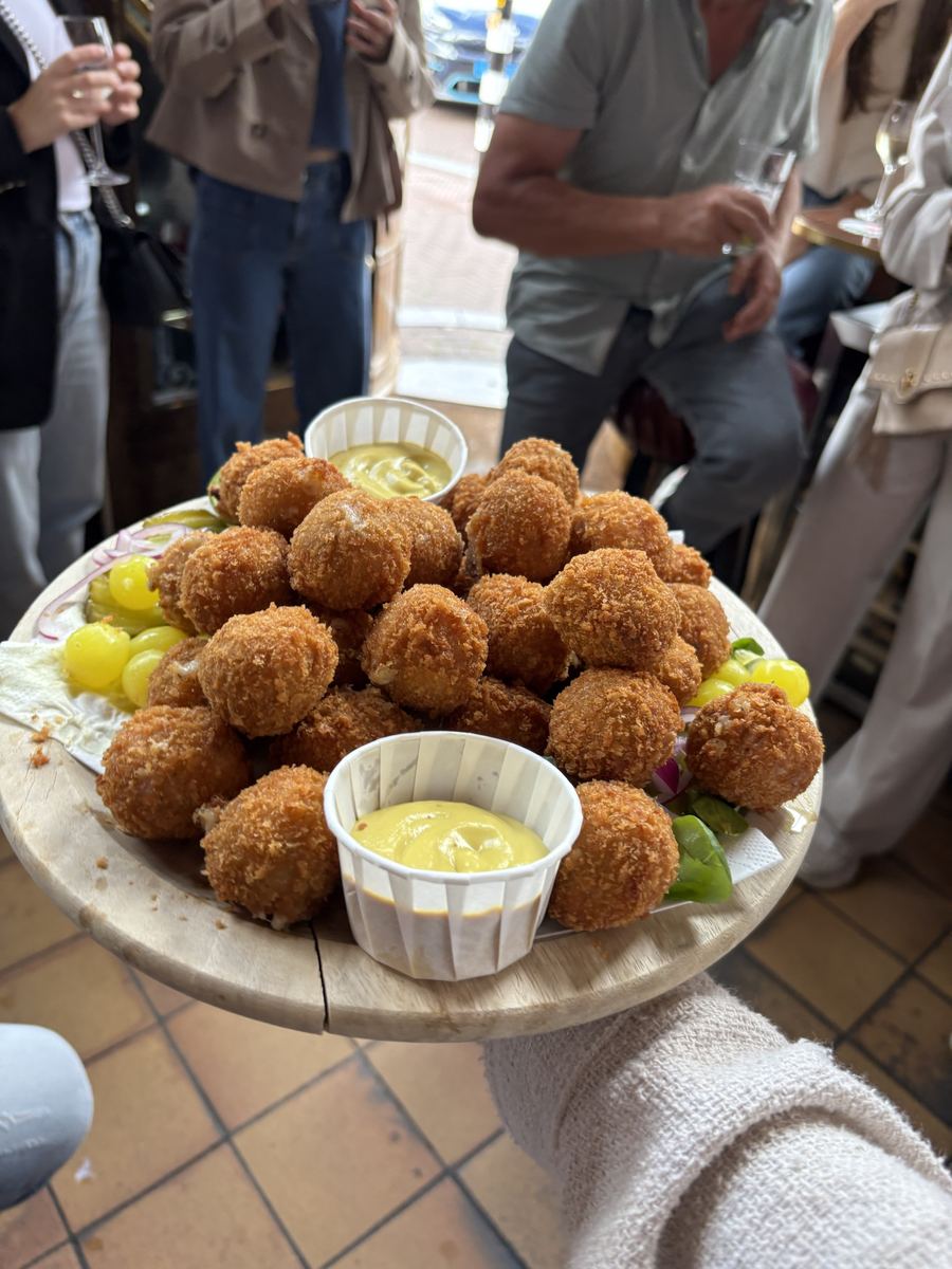 Wooden board piled high with golden bitterballen and mustard in a brown café