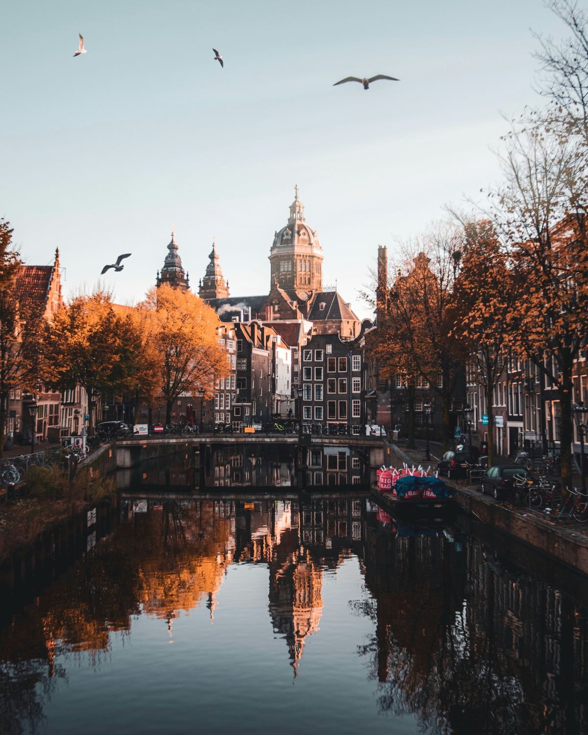 Canal with bridge, autumn trees and the dome of the Sint-Nicolaaskerk reflected in the water