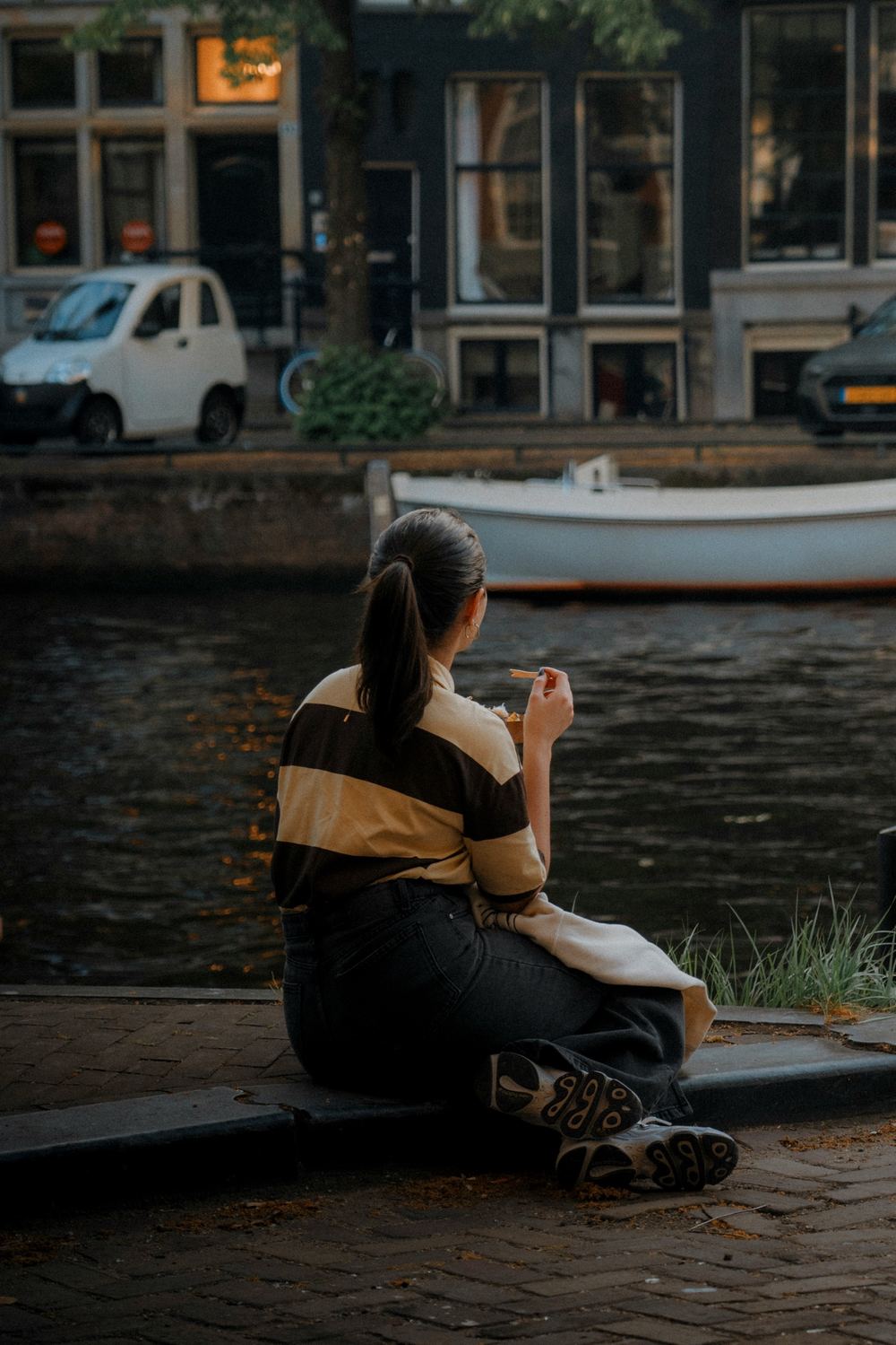 Woman eating a snack on the edge of a canal